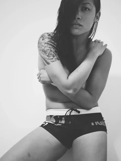 Black and white editorial portrait of Katty Strite with a shoulder tattoo, arms crossed over her chest