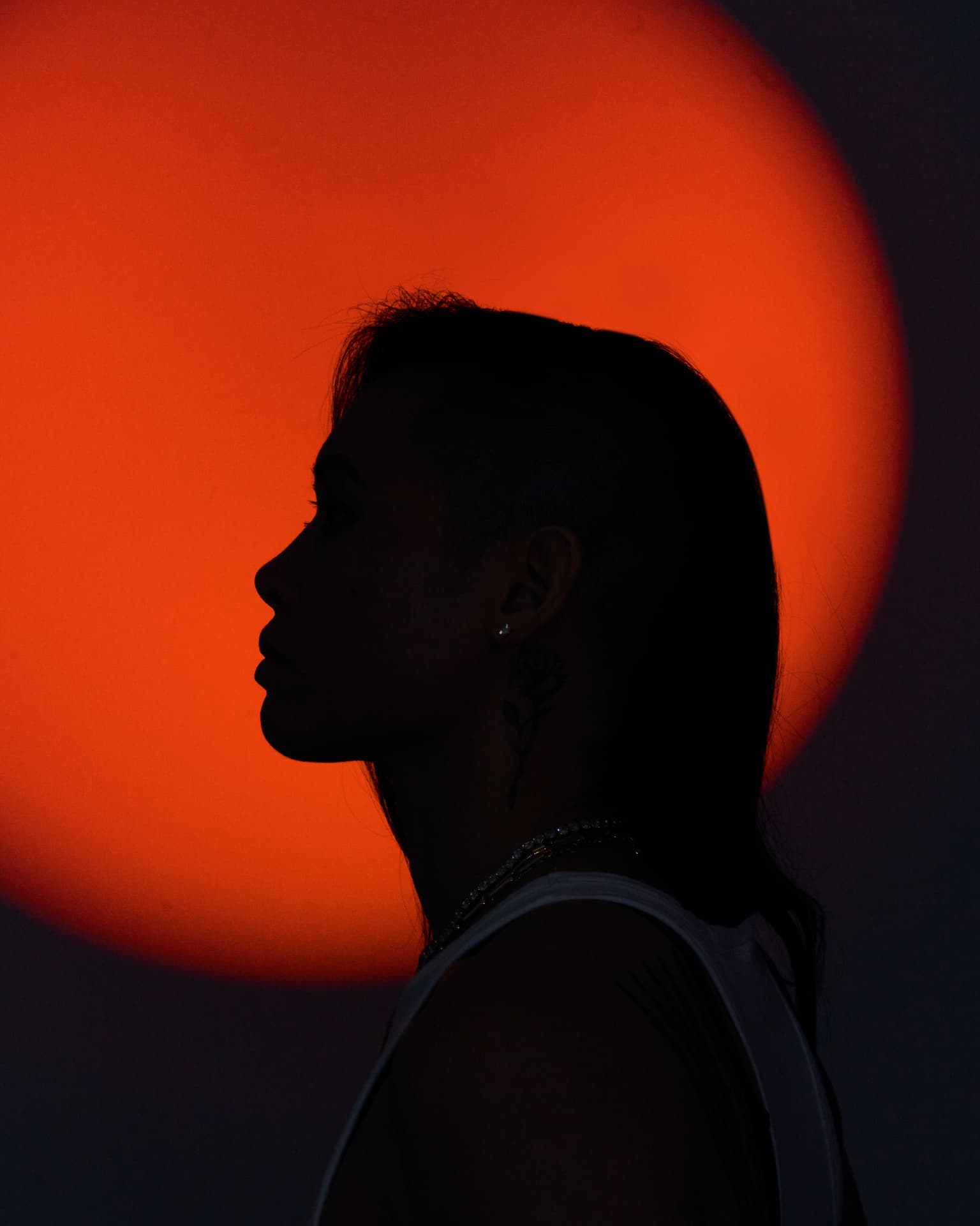 Silhouette profile portrait of Katty Strite against a deep orange glow