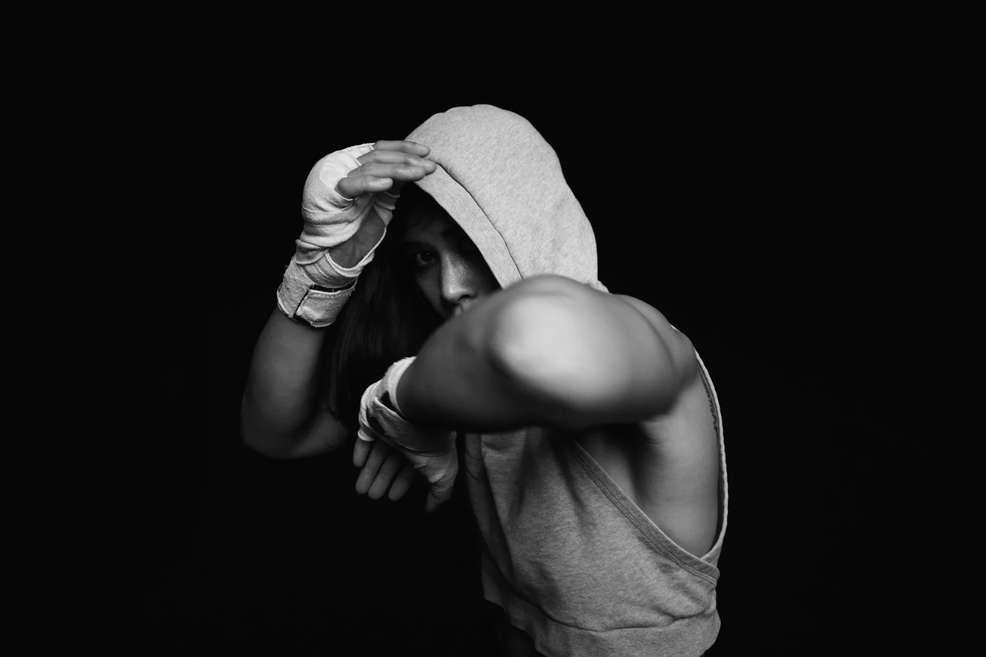 Katty Strite in a hooded top with wrapped hands, guard up, photographed against black