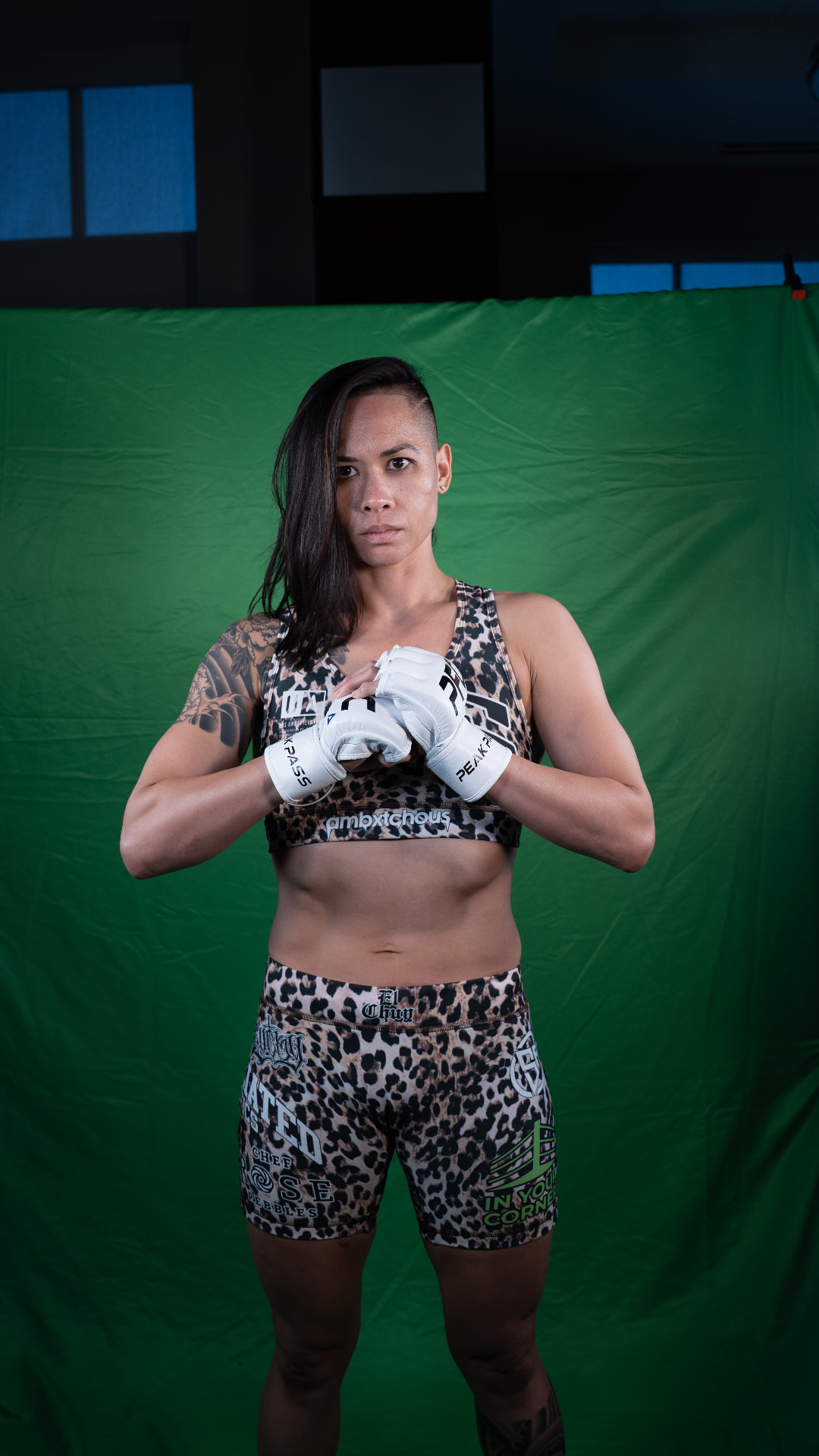 Katty Strite in Peak fight gear, gloves crossed, in front of a green screen